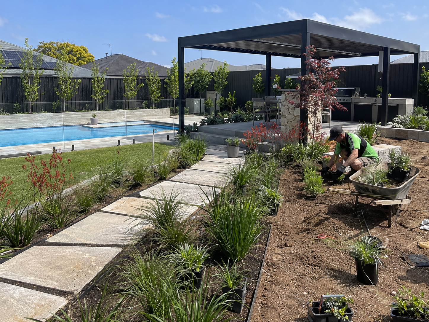 Landscaper planting a garden beside a pool and outdoor entertaining area